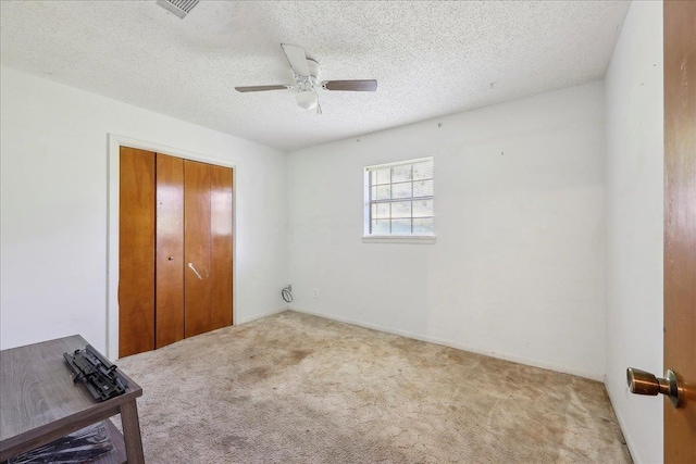 unfurnished bedroom with carpet, a closet, a textured ceiling, and ceiling fan