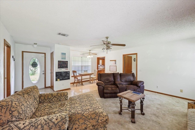 living area with visible vents, a textured ceiling, baseboards, and ceiling fan