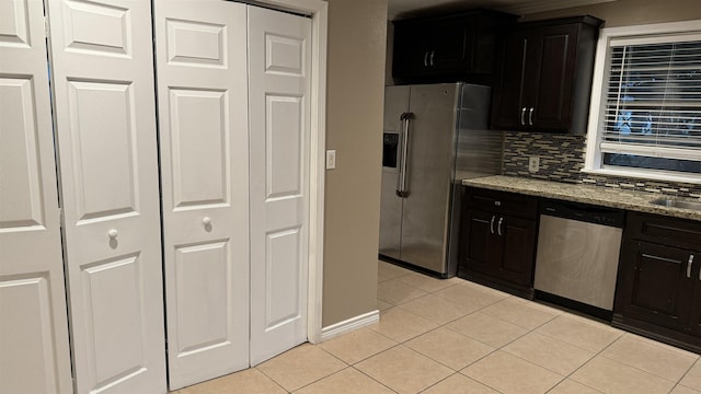 kitchen with sink, light tile patterned floors, appliances with stainless steel finishes, tasteful backsplash, and light stone counters