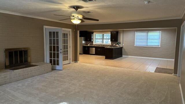 unfurnished living room with a textured ceiling, a fireplace, light colored carpet, and french doors