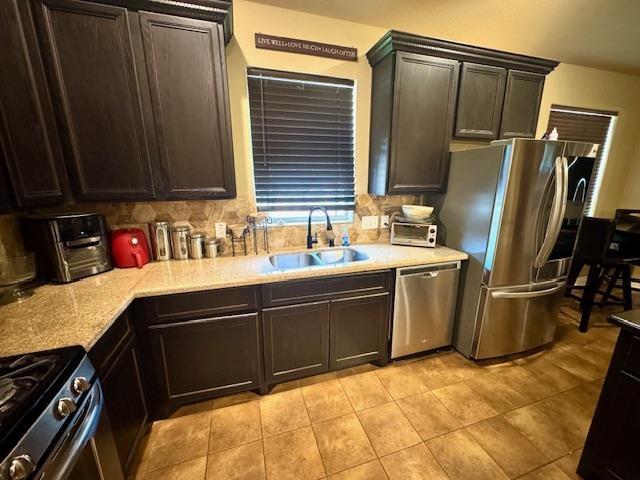 9265 N Sage, Beaumont, TX 77713 - kitchen with appliances with stainless steel finishes, decorative backsplash, light tile patterned floors, and dark brown cabinetry