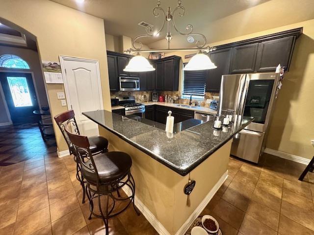 9265 N Sage, Beaumont, TX 77713 - kitchen with appliances with stainless steel finishes, a center island, tasteful backsplash, dark stone countertops, and tile patterned flooring