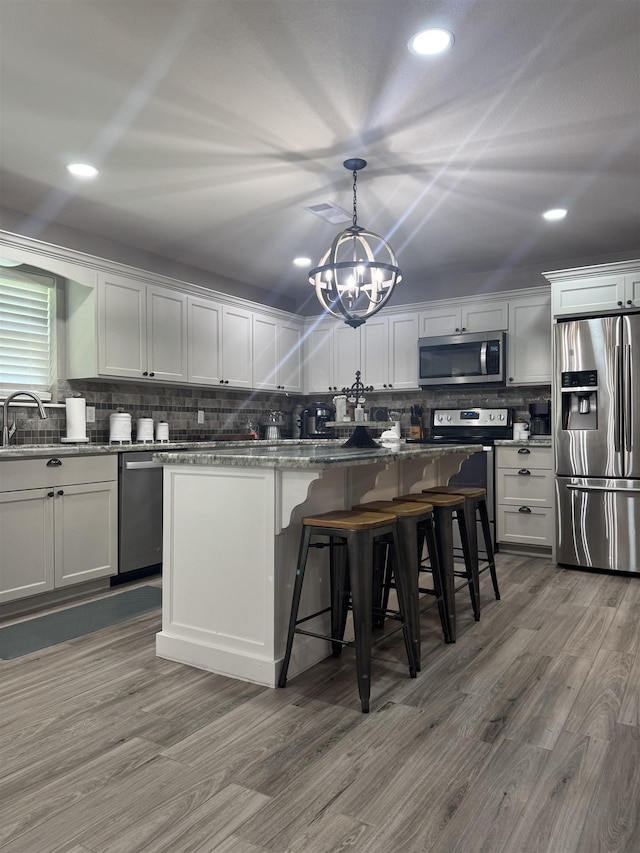 2211 Summer Oak Ln, Orange, TX 77632 - kitchen with stainless steel appliances, a chandelier, decorative backsplash, wood finished floors, and recessed lighting