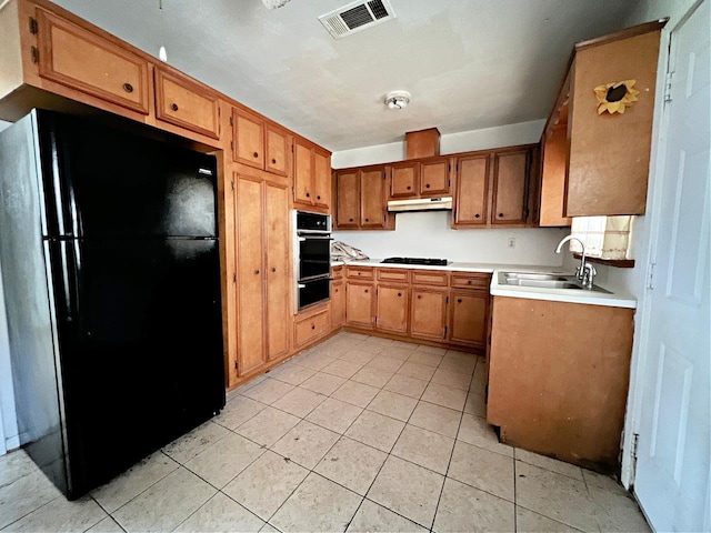 833 W 6th St, Port Arthur, TX 77640 - kitchen with black appliances, under cabinet range hood, a warming drawer, light tile patterned floors, and brown cabinetry