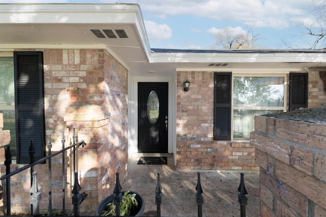 view of exterior entry featuring visible vents and brick siding