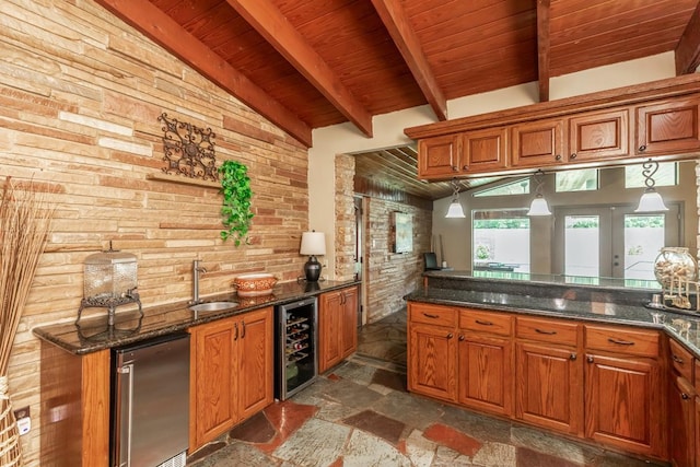 kitchen featuring pendant lighting, dark stone counters, refrigerator, sink, and wine cooler