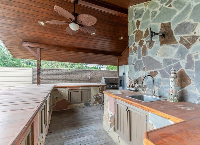 view of patio with ceiling fan, a grill, exterior kitchen, and sink