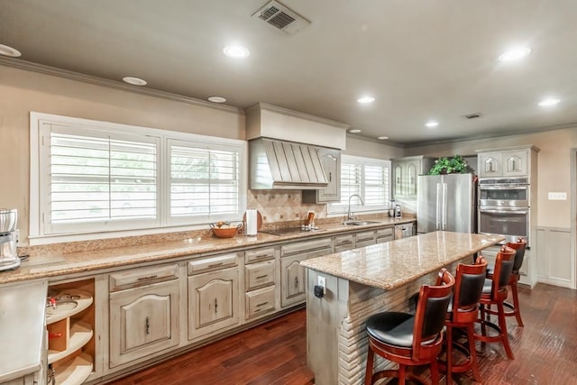 kitchen featuring appliances with stainless steel finishes, dark hardwood / wood-style flooring, a breakfast bar, sink, and a center island