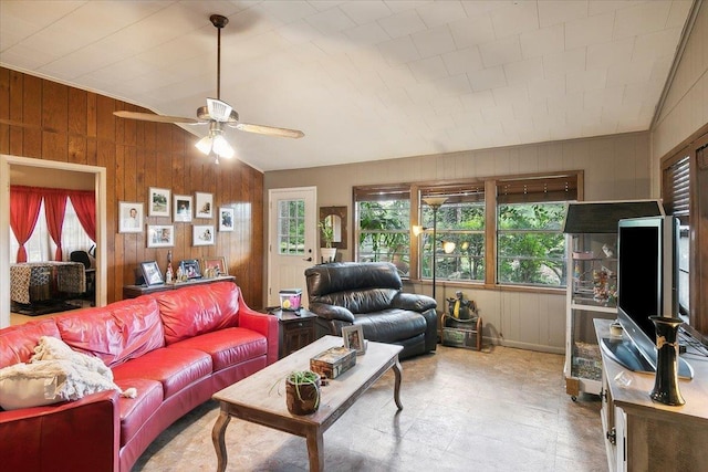 living room with vaulted ceiling, ceiling fan, and wood walls