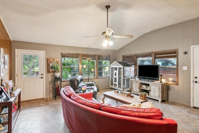 living room with ceiling fan, wood walls, and lofted ceiling