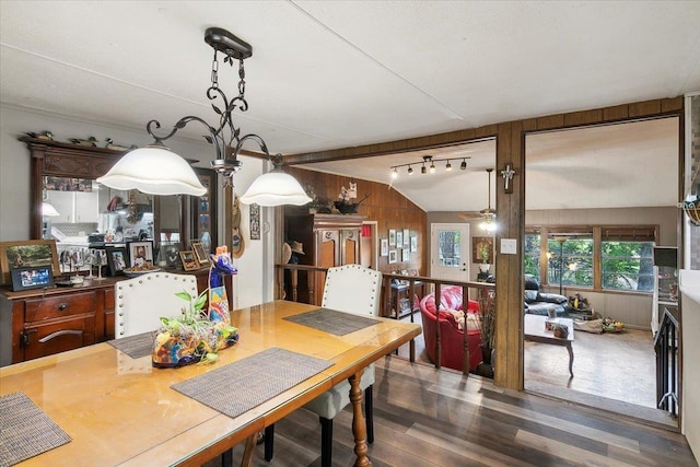 dining area featuring dark wood-type flooring, lofted ceiling, and wood walls