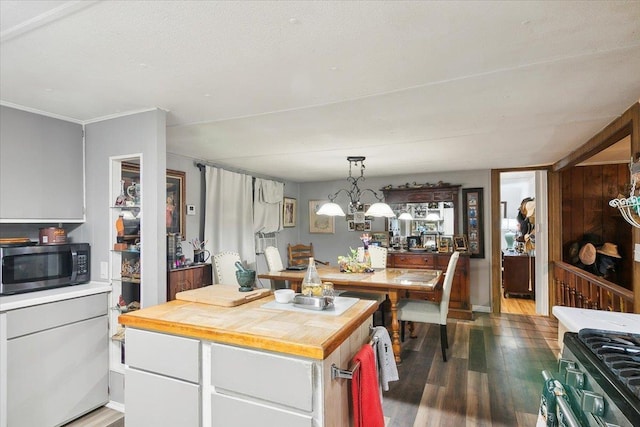 kitchen featuring white cabinetry, stainless steel appliances, dark hardwood / wood-style floors, a notable chandelier, and pendant lighting