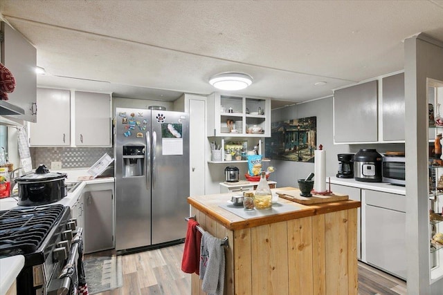 kitchen featuring backsplash, a textured ceiling, stainless steel appliances, light hardwood / wood-style floors, and white cabinetry