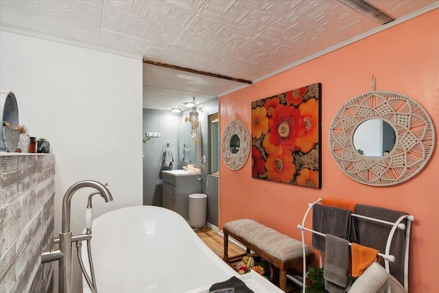 bathroom with a tub, hardwood / wood-style flooring, vanity, and ornamental molding