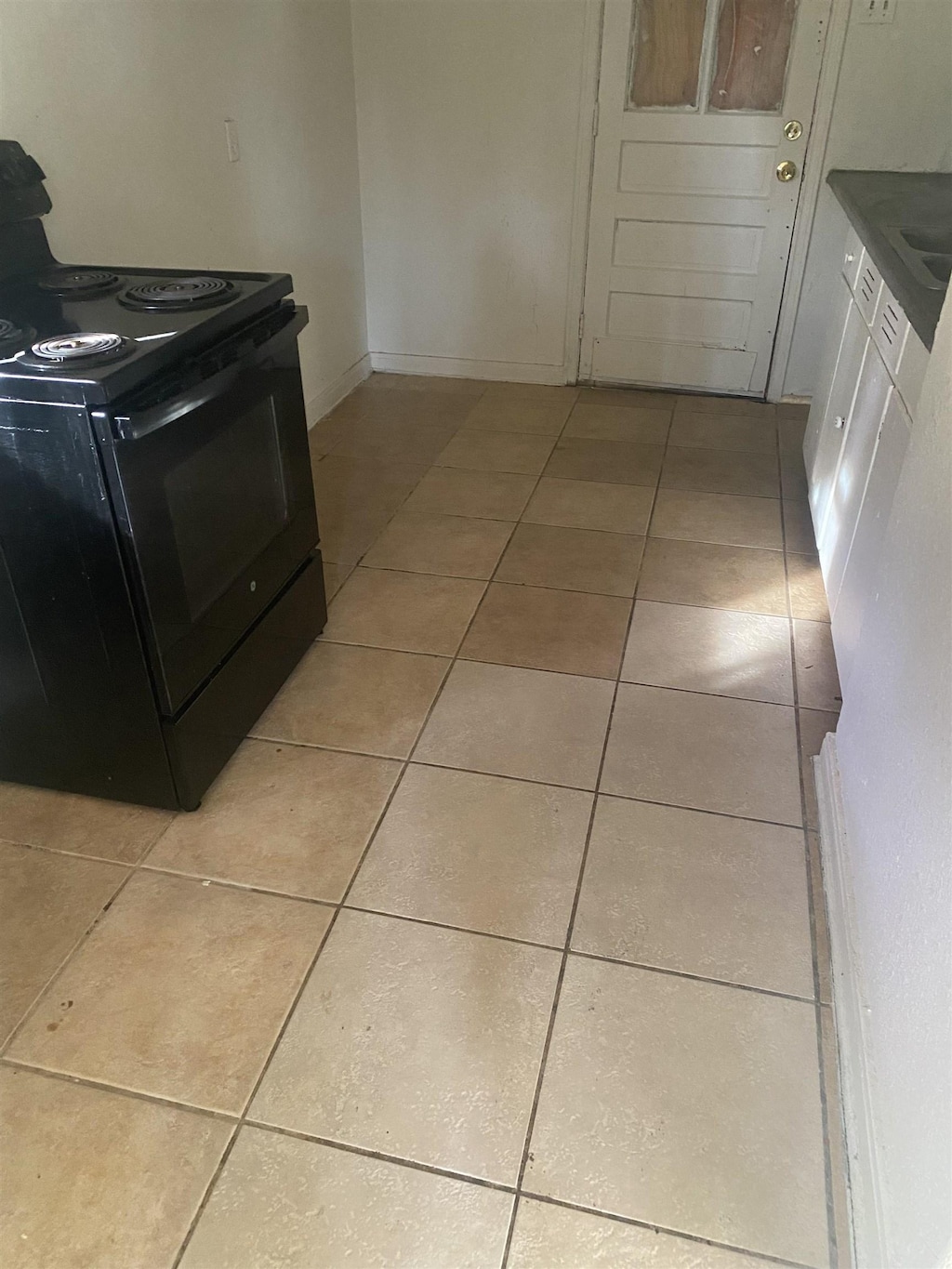 kitchen with light tile patterned floors and black range with electric cooktop