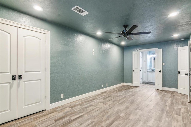 empty room featuring ceiling fan, light hardwood / wood-style floors, and a textured ceiling