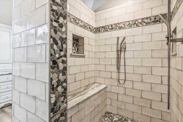 bathroom featuring a tile shower and wood-type flooring