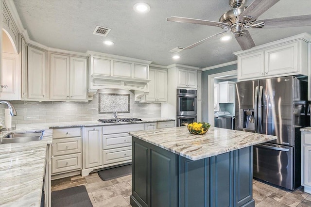 kitchen featuring appliances with stainless steel finishes, independent washer and dryer, light stone counters, and sink