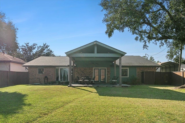 back of property with a yard, a carport, and ceiling fan