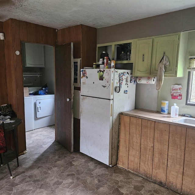 kitchen with washing machine and dryer, sink, a textured ceiling, and white refrigerator