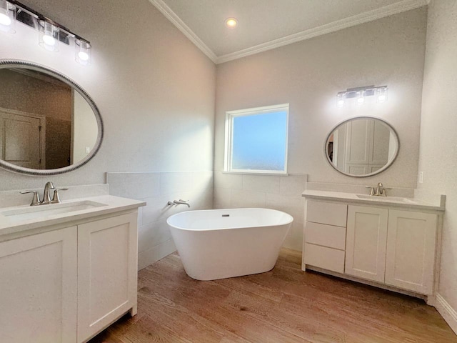 bathroom featuring a tub to relax in, ornamental molding, vanity, wood-type flooring, and tile walls