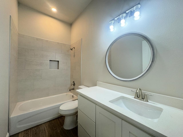 full bathroom featuring hardwood / wood-style floors, tiled shower / bath combo, toilet, and vanity