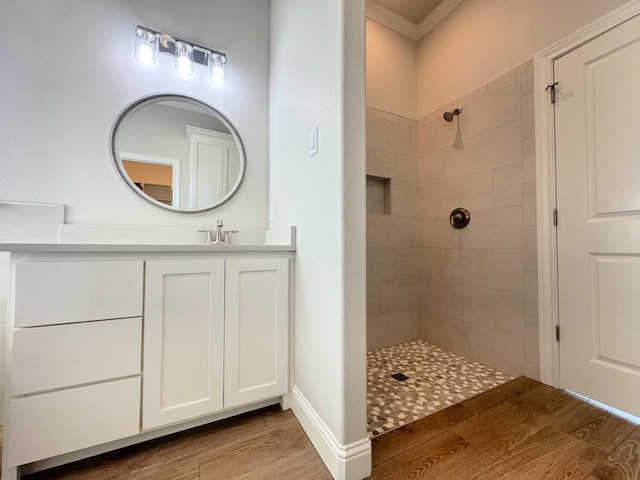 bathroom with vanity, a tile shower, wood-type flooring, and crown molding