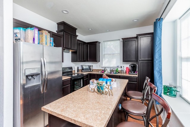 kitchen featuring a center island, sink, dark brown cabinets, a kitchen bar, and stainless steel appliances