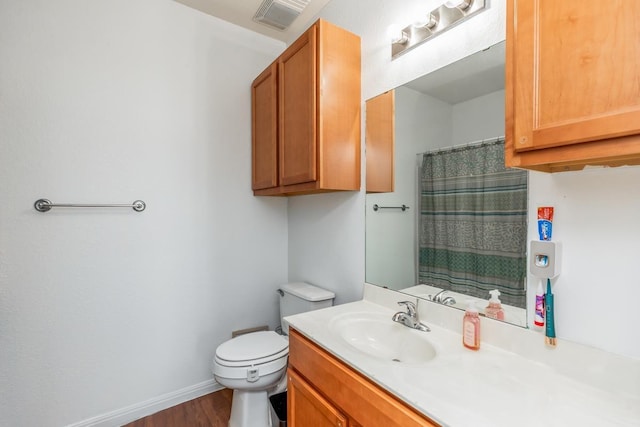 bathroom with walk in shower, hardwood / wood-style floors, vanity, and toilet