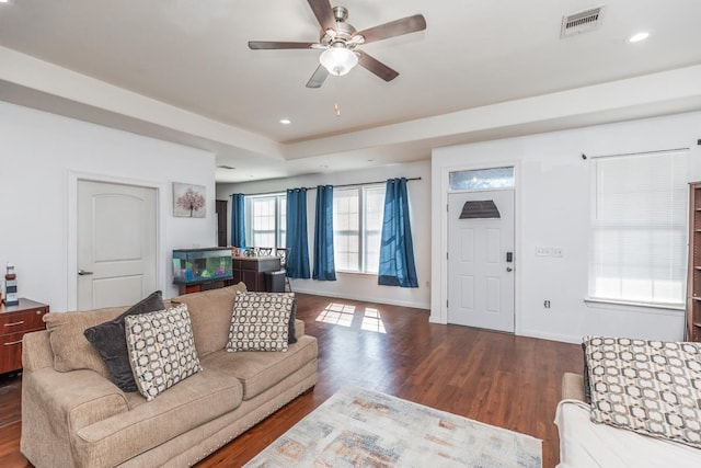 living room with dark hardwood / wood-style floors, ceiling fan, and a tray ceiling