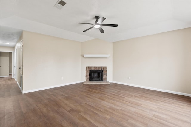 unfurnished living room with ceiling fan, vaulted ceiling, a brick fireplace, and light wood-type flooring