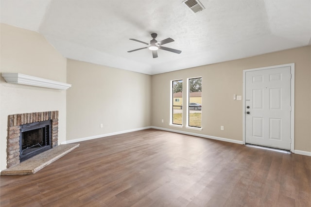 unfurnished living room featuring dark hardwood / wood-style floors, lofted ceiling, ceiling fan, a brick fireplace, and a textured ceiling