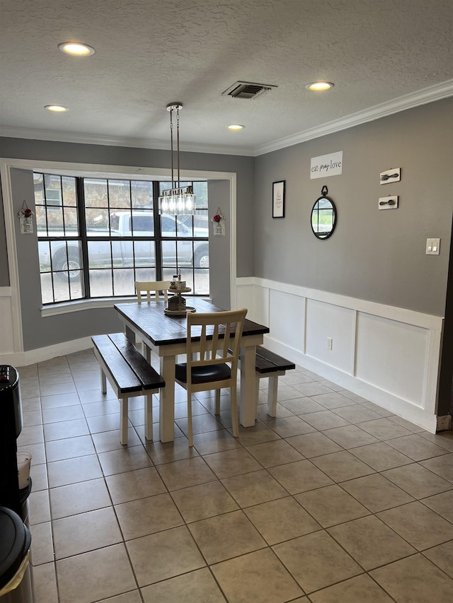 tiled dining area with crown molding and a textured ceiling