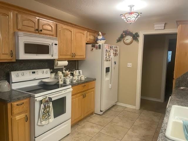 kitchen with backsplash, light tile patterned flooring, white appliances, and sink