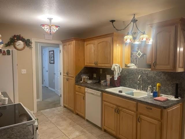 kitchen with tasteful backsplash, white appliances, sink, pendant lighting, and a notable chandelier