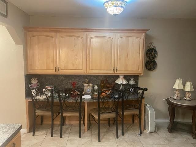 bar featuring light brown cabinets and tasteful backsplash