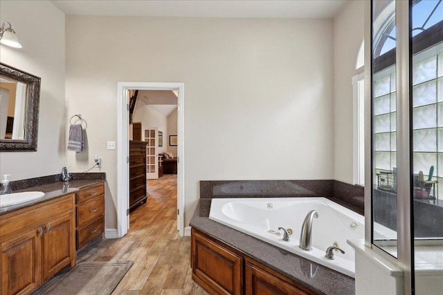 2801 Magnolia Ln, Groves, TX 77619 - bathroom with vanity, a tub with jets, and wood finished floors