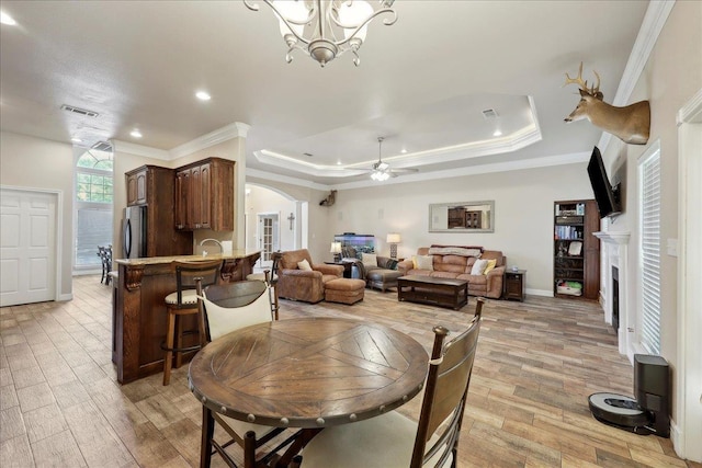2801 Magnolia Ln, Groves, TX 77619 - dining area featuring a fireplace, ornamental molding, light wood-type flooring, arched walkways, and ceiling fan
