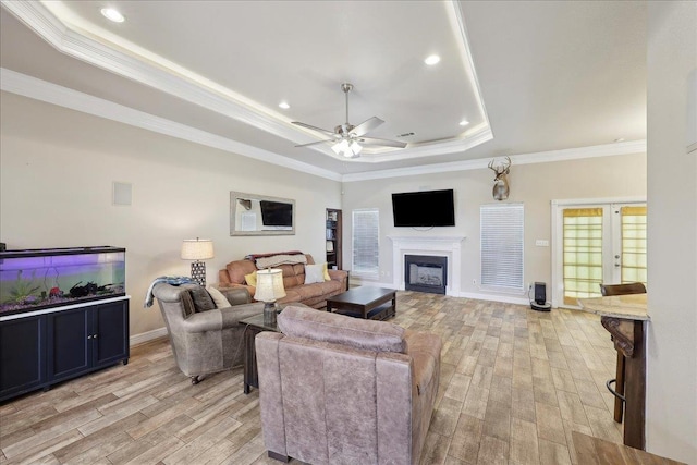 2801 Magnolia Ln, Groves, TX 77619 - living room with a tray ceiling, light wood-style flooring, ceiling fan, ornamental molding, and a fireplace