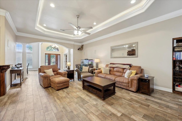 2801 Magnolia Ln, Groves, TX 77619 - living room with ornate columns, arched walkways, light wood-type flooring, a tray ceiling, and ornamental molding