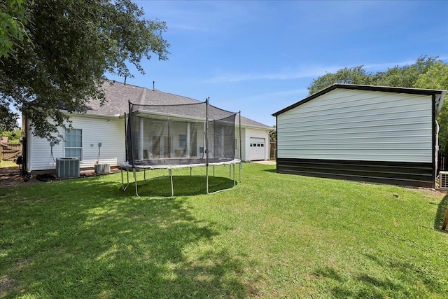 2801 Magnolia Ln, Groves, TX 77619 - back of property with a trampoline, a yard, an outdoor structure, a garage, and central AC