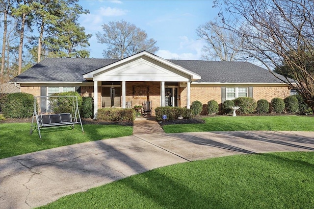 neoclassical home with roof with shingles, a front yard, and brick siding