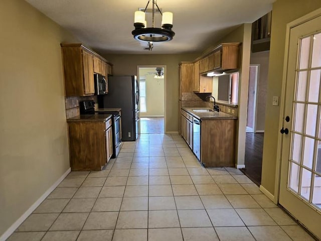 kitchen featuring stainless steel appliances, a sink, dark countertops, baseboards, and decorative backsplash