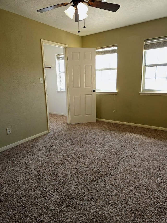 unfurnished room with carpet, a textured ceiling, a ceiling fan, and baseboards