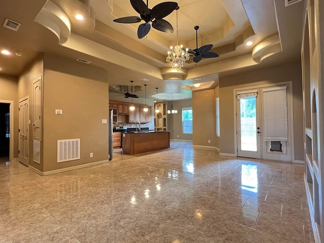 kitchen with open floor plan, a tray ceiling, dark countertops, and visible vents