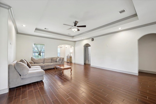 4592 Shakespeare Ln, Kountze, TX 77625 - living room featuring arched walkways, a raised ceiling, ceiling fan, dark wood-style flooring, and crown molding