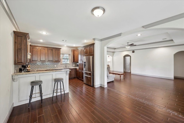 4592 Shakespeare Ln, Kountze, TX 77625 - kitchen featuring arched walkways, stainless steel refrigerator with ice dispenser, a peninsula, a ceiling fan, and crown molding