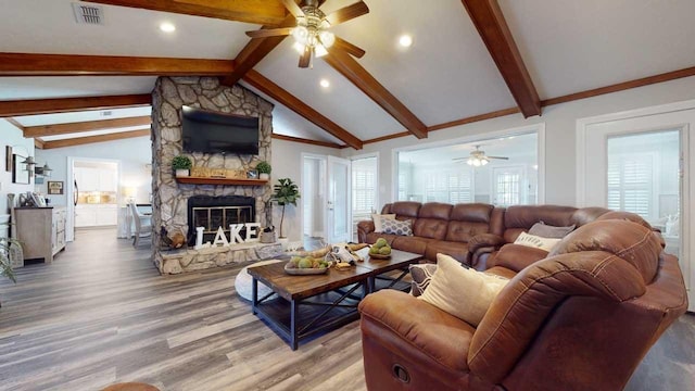 living room with hardwood / wood-style floors, vaulted ceiling with beams, ceiling fan, a fireplace, and a wealth of natural light