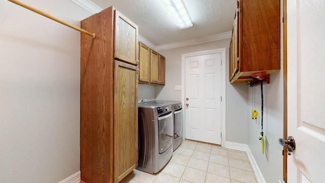 washroom with washing machine and dryer, cabinets, a textured ceiling, and ornamental molding