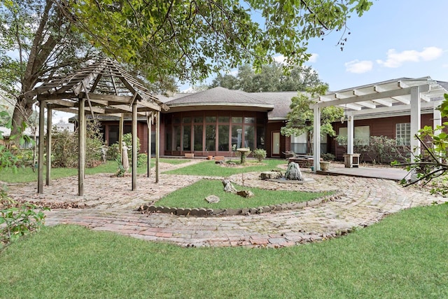 back of house featuring a sunroom, a pergola, and a lawn